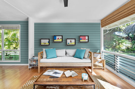 Affiches BD architecture 4 cases au-dessus d'une banquette en bois dans un salon donnant sur jardin tropical