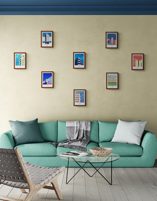 Huit affiches picturales Berlin sur mur beige au-dessus d'un grand canapé vert sur terrasse en bois style bord de mer chic