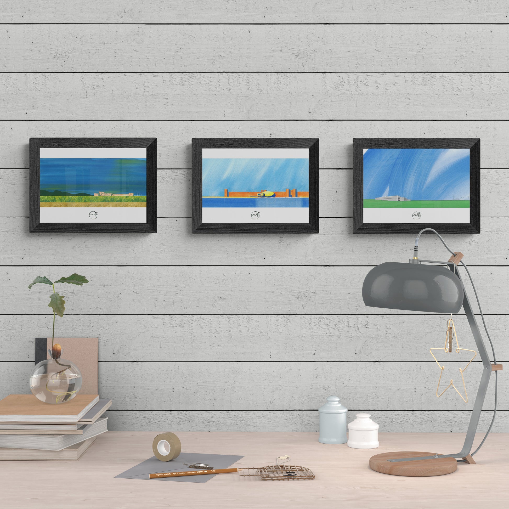 Trois affiches picturales paysages architecture dans la campagne française au-dessus d'un plan de travail avec lampe d'atelier