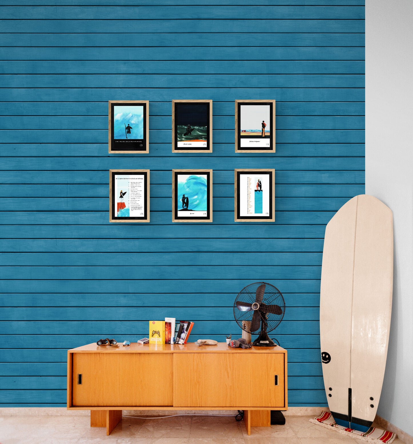 6 affiches picturales surf au-dessus d'un buffet vintage et d'une planche de surf sur mur en bois bleu