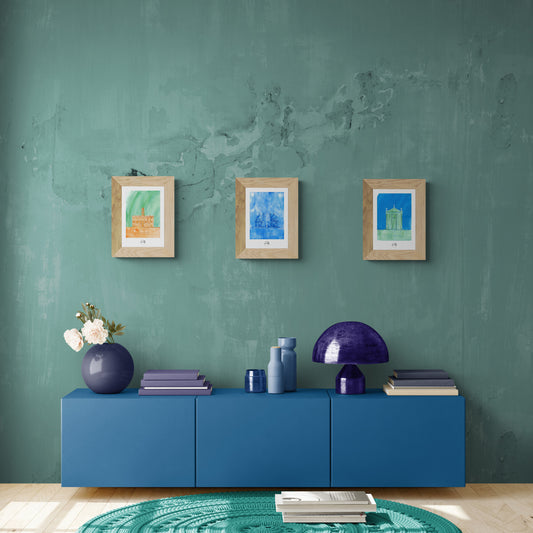 Trio d'affiches picturales colorées de monuments romains sur mur vert au-dessus d'un buffet bleu