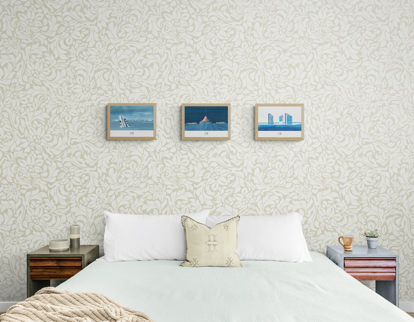 Trois affiches picturales architecture au-dessus d'un lit dans une chambre avec papier peint pastel